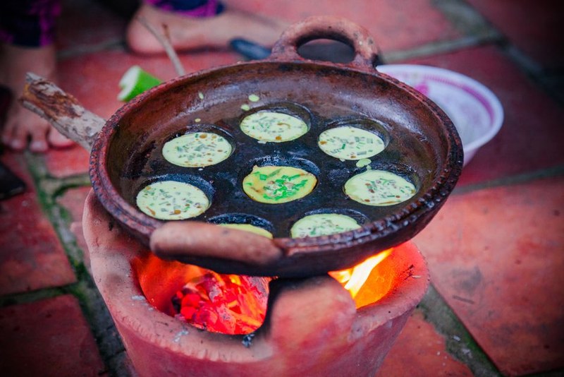 Khuôn bánh căn trên bếp với bánh đang chín