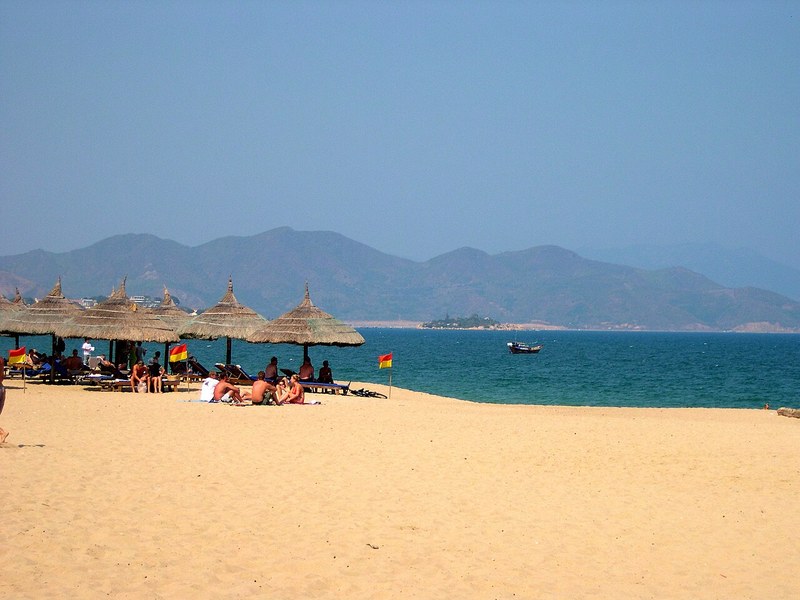 Bãi biển Nha Trang với dù lá, phía xa là núi