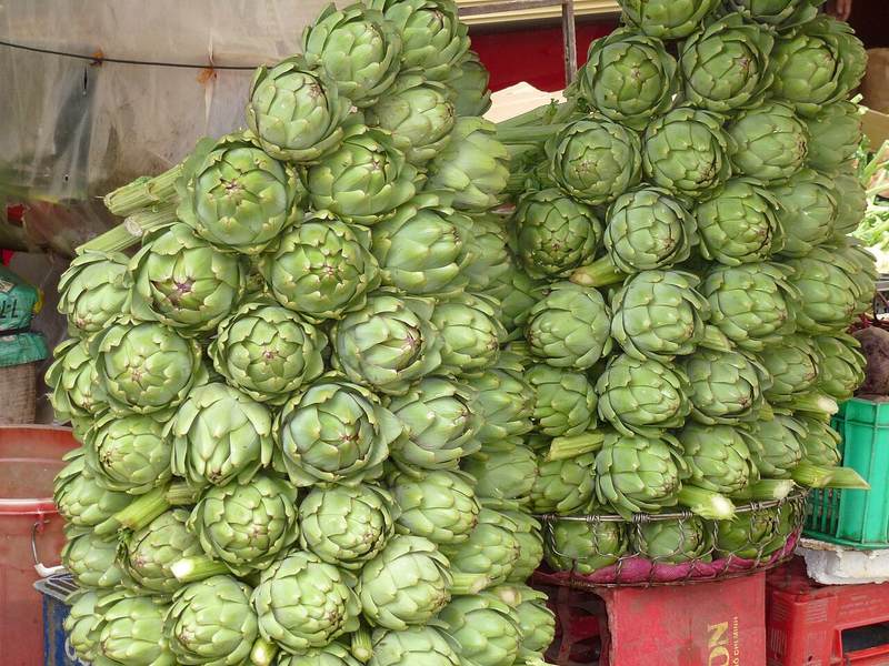 Bông atiso tươi chất thành đống tại một sạp ở chợ Đà Lạt