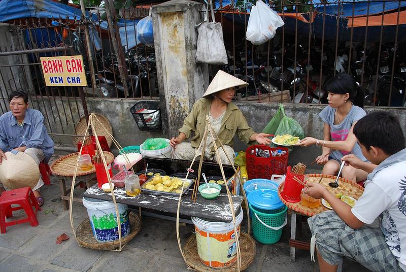 Gánh bánh căn ven đường với bếp khuôn đất và ghế nhựa