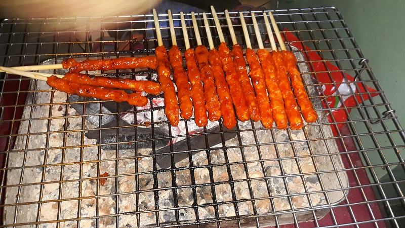 Những xiên nem nướng màu đỏ cam trên vỉ nướng